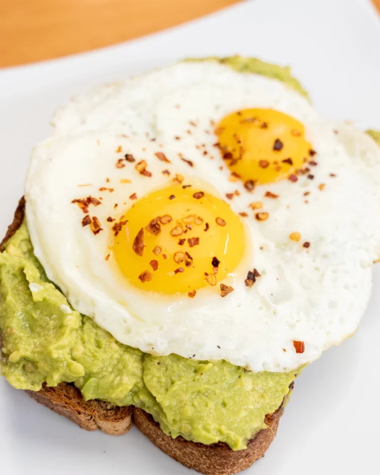 Avocado toast topped with two fried eggs and chili flakes, a healthy breakfast option at Mango Mango in Bonita, CA